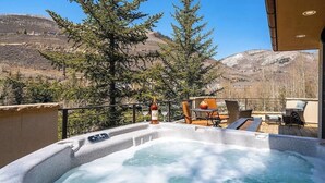 Un jacuzzi con vista a la montaña, rodeado de mobiliario exterior y una barandilla.