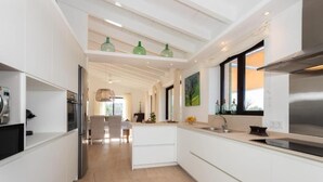 A modern kitchen with white cabinetry, a stainless steel range hood, and a large window providing natural light. - Finca Aubaco
Stunning Finca with pool and garden (PM)
