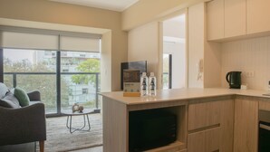 Una cocina moderna con microondas integrado, cafetera y una pequeña mesa con botellas.