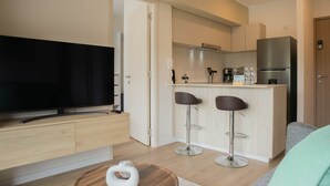 Una sala de estar moderna con un televisor de pantalla plana, una mesa de centro de madera y dos taburetes de bar.