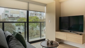 Una sala de estar moderna con un ventanal grande, un televisor de pantalla plana y un mueble de madera minimalista.