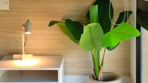 A modern room with a wooden wall, a white desk with a lamp, and a large potted plant. - NOK Perfect Duplex in El Poblado (Medellín)