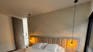 A modern bedroom with a large bed, bedside tables, and pendant lights. - NOK Perfect Duplex in El Poblado (Medellín)