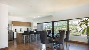 A modern kitchen with a dining area, large windows with a city view, and a plant on the windowsill. - NOK Perfect Duplex in El Poblado (Medellín)