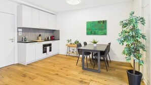 Una cocina moderna con armarios blancos, encimera negra y un comedor con mesa y sillas.