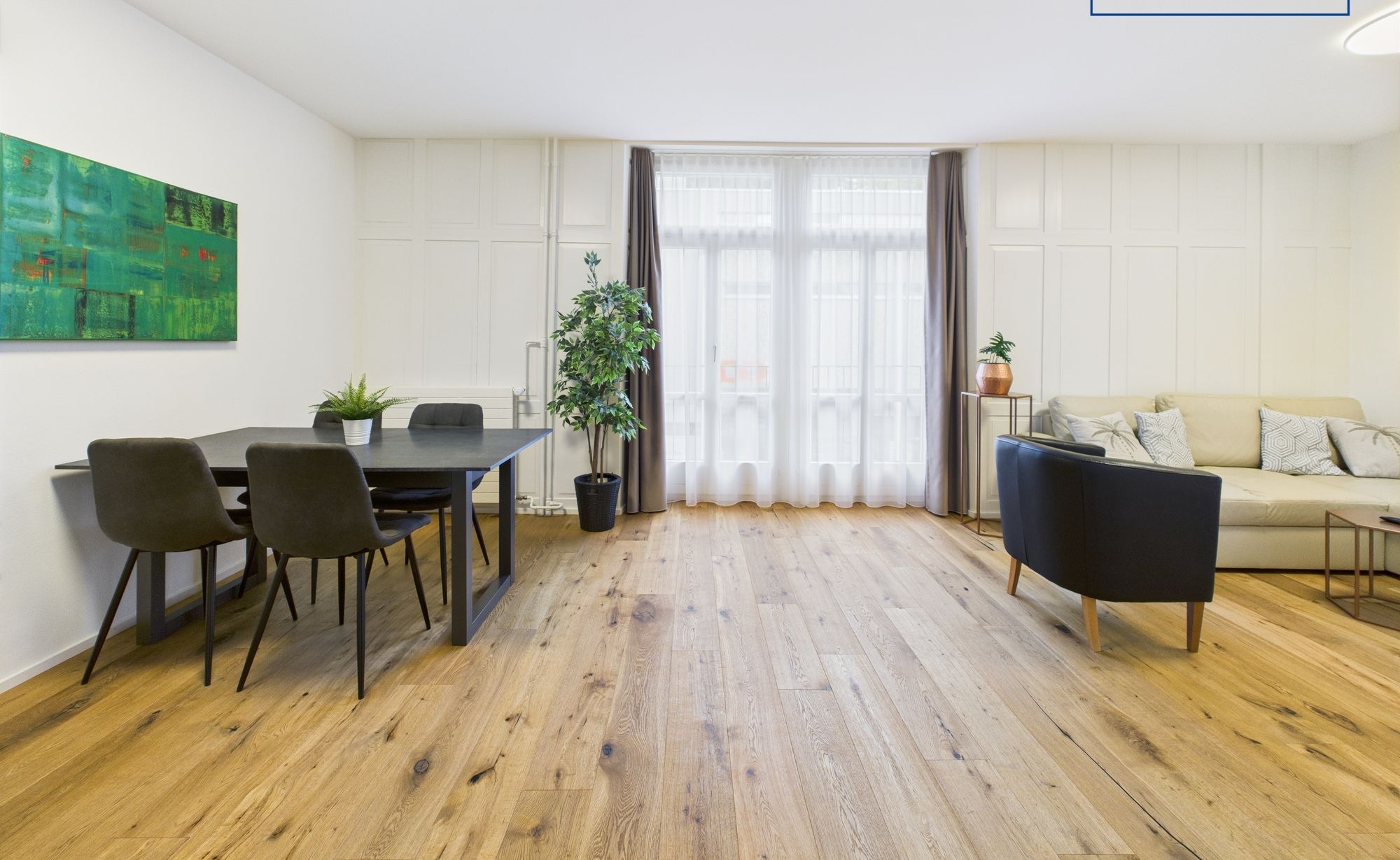 Ein modernes Wohnzimmer mit Essbereich, mit Holzboden, einer Couch, einem Couchtisch und einem Esstisch mit Stühlen.
