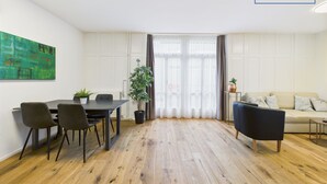 Una sala de estar moderna con comedor, que presenta piso de madera, un sofá, una mesa de centro y una mesa de comedor con sillas.