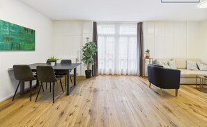 Un salon moderne avec un coin repas, comprenant un plancher en bois, un canapé, une table basse et une table à manger avec des chaises.