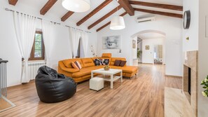 Un salon avec un canapé, une table basse, un fauteuil poire et une cheminée.