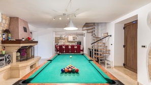 Une table de billard avec des billes, une cheminée, un coin repas et un escalier.