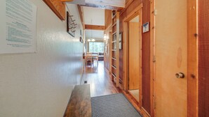 Un pasillo interior de madera con un banco, una puerta y una ventana al final.