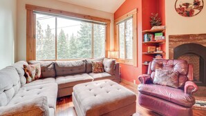 Una sala de estar con sofá modular, reposapiés, sillón de cuero y chimenea.