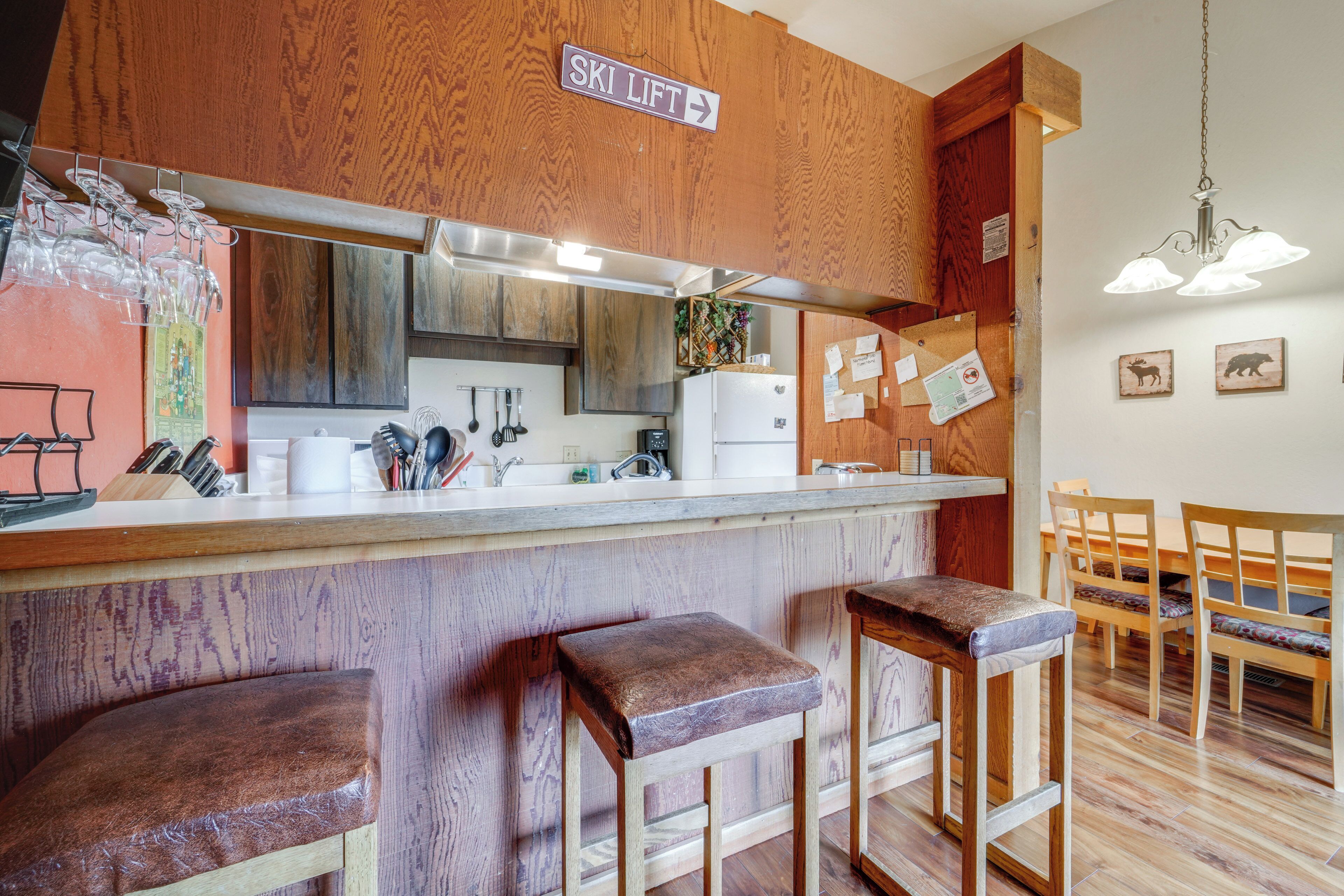 A kitchen with wooden cabinets, a bar area with stools, and a sign indicating a ski lift direction.
