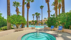 Une piscine de forme circulaire, entourée de palmiers et de chaises longues bleues.