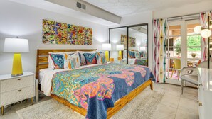 Une chambre à coucher avec un grand lit, une table de chevet, une lampe, un miroir et une vue sur l’extérieur.
