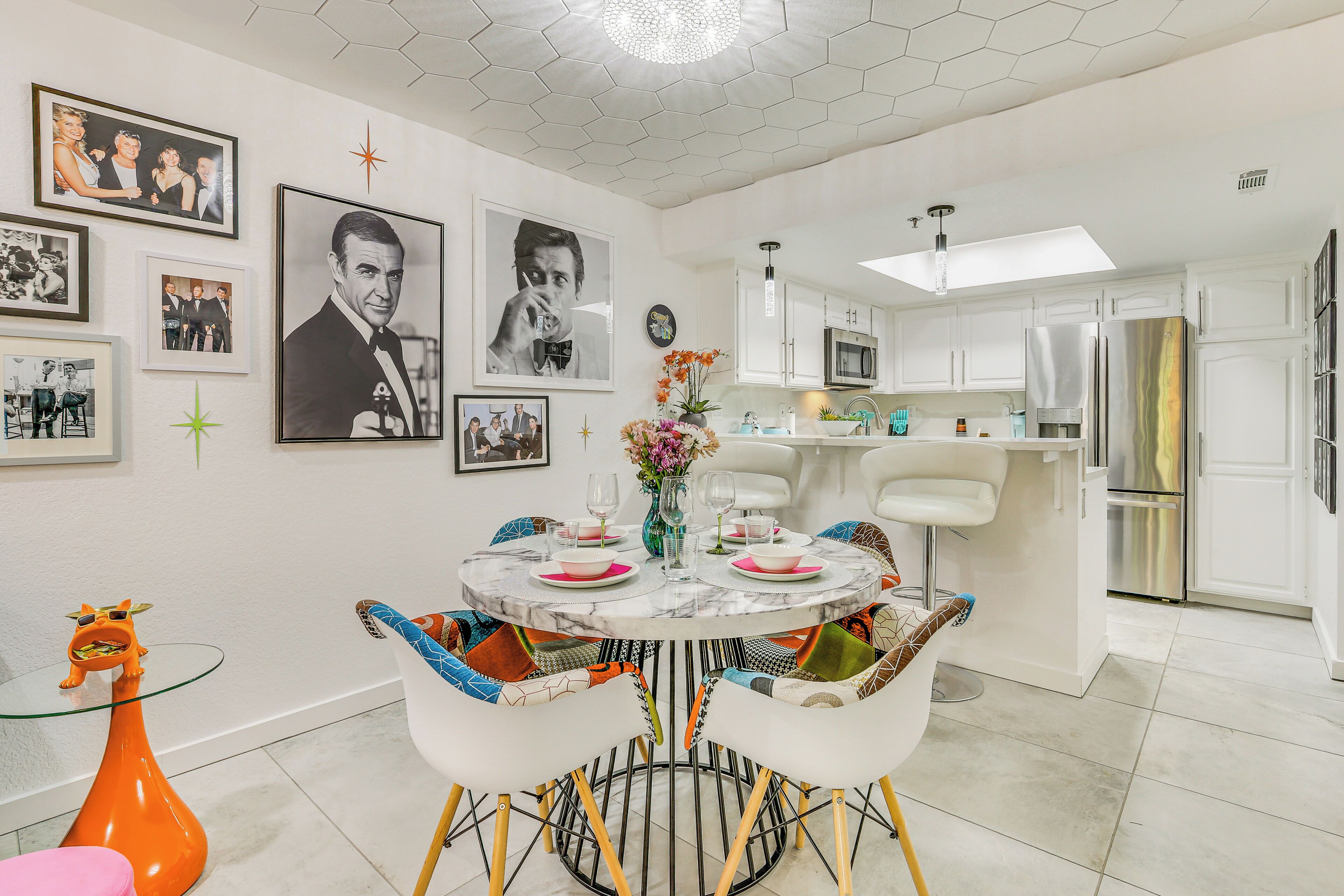 A modern kitchen with white cabinets, stainless steel appliances, and a dining area with a round table and colorful chairs.
