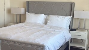 Ein ordentlich bezogenes Bett mit weißen Leinen in einem Zimmer mit Holzboden.