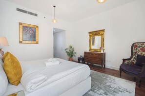 A hotel room with a bed, a dresser, a chair, and a mirror.
