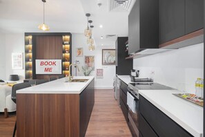Una cocina moderna con una isla central, electrodomésticos integrados y un cartel que dice 'BOOK ME'.