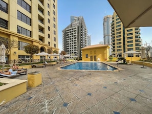 Uma área de piscina no terraço, com piscina, espreguiçadeiras e guarda-sóis.