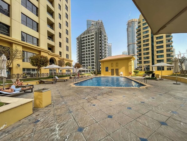 A rooftop pool area with a swimming pool, lounge chairs, and umbrellas.