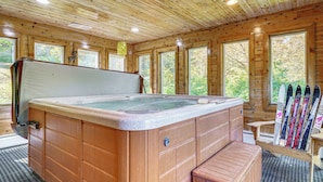 A wooden cabin with a hot tub, wooden benches, and skis leaning against the wall. - Riverfront Home w/ Hot Tub Near Killington Resort (Bridgewater Corners)
