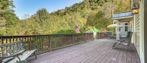 A wooden deck with a bench, a flag, and a building with a porch.