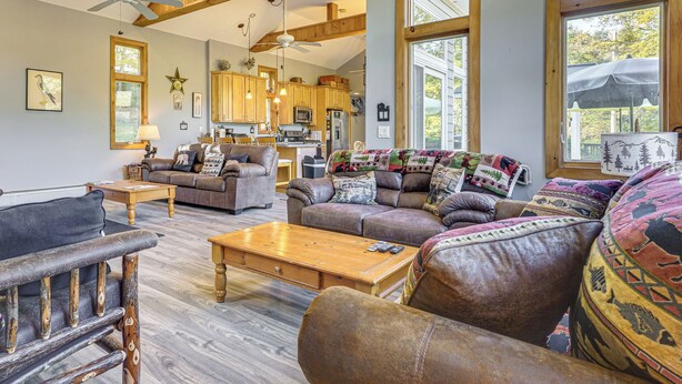 A spacious living room with leather sofas, a wooden coffee table, and a ceiling fan. - Riverfront Home w/ Hot Tub Near Killington Resort (Bridgewater Corners)