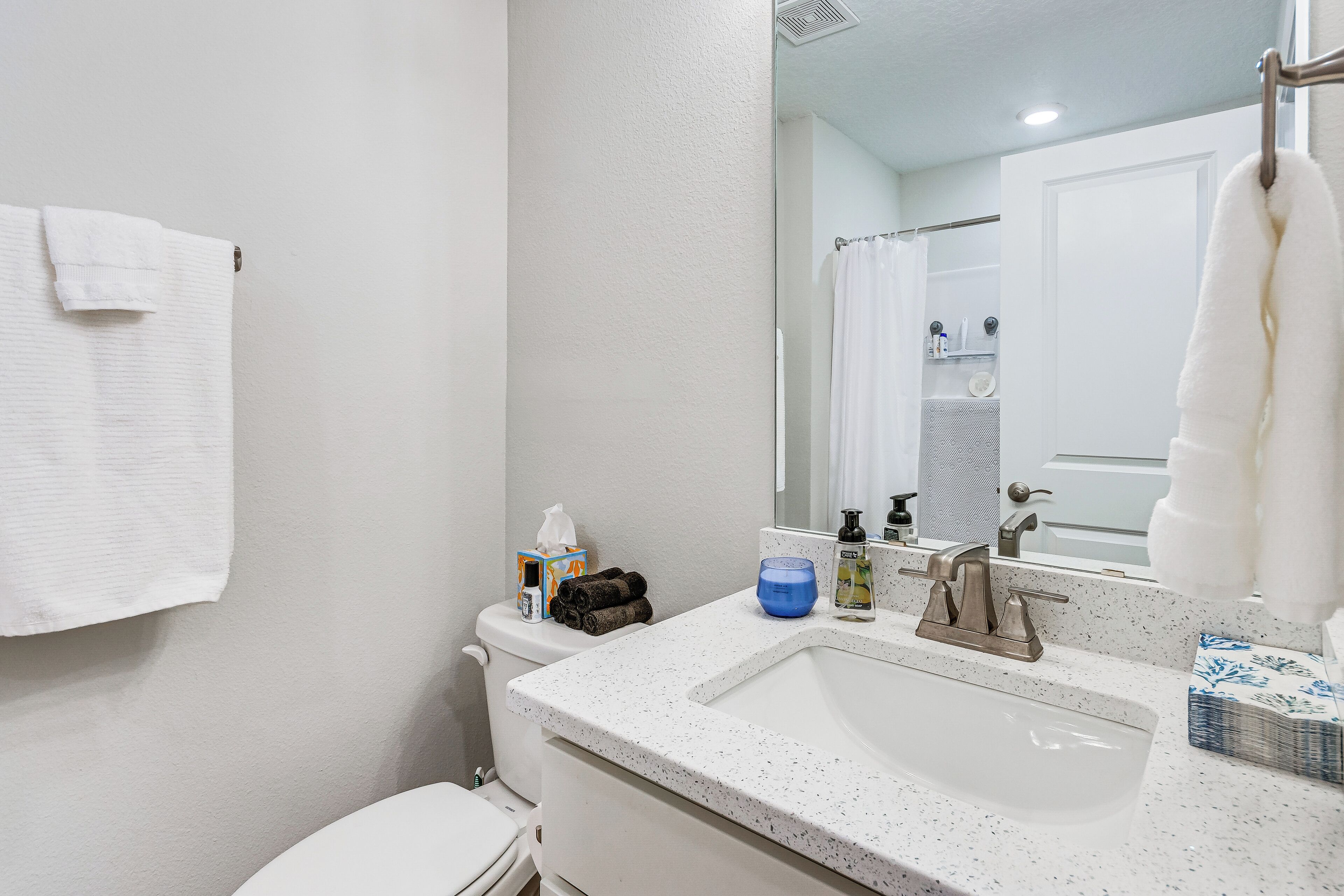 Une salle de bain avec un lavabo blanc, un miroir et une serviette accrochée au mur.