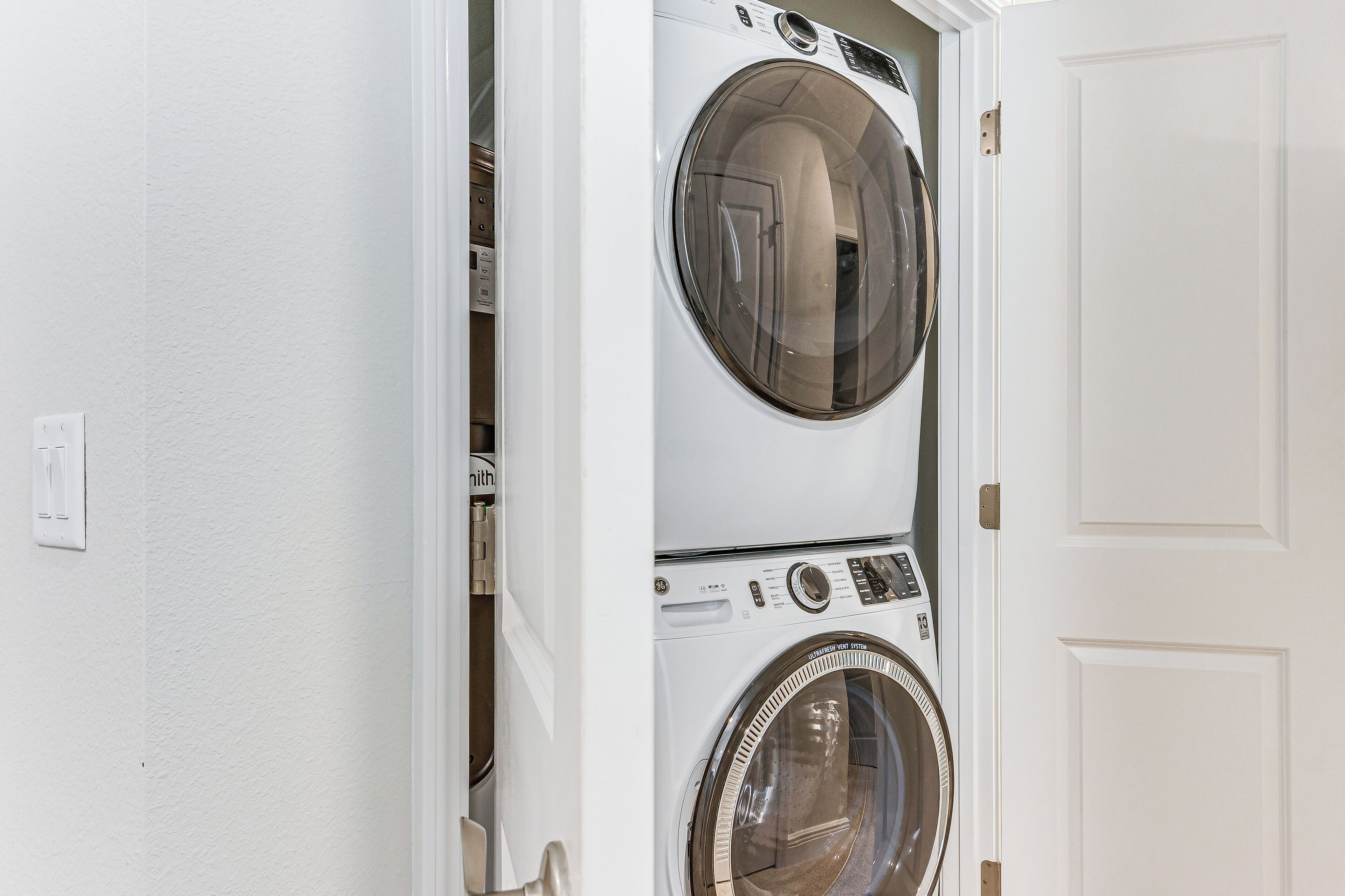 A laundry room with two stacked front-loading washing machines and a door.