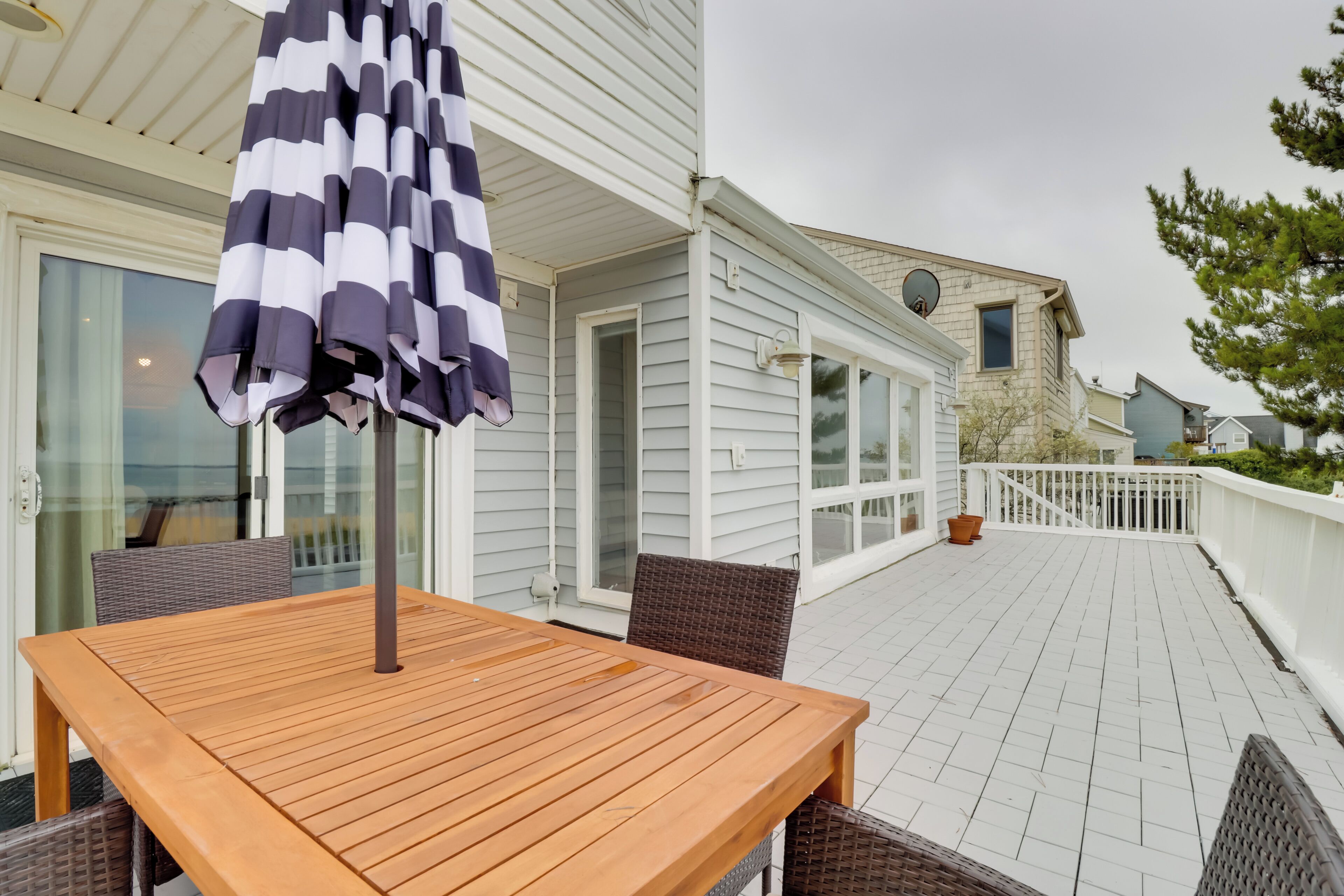 A wooden deck with a table and chairs, an umbrella, and a white railing.