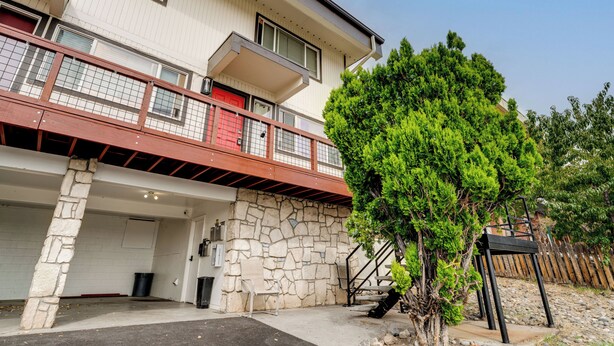 Un edificio a più piani con facciata in pietra, una porta rossa e un balcone con ringhiera in metallo.