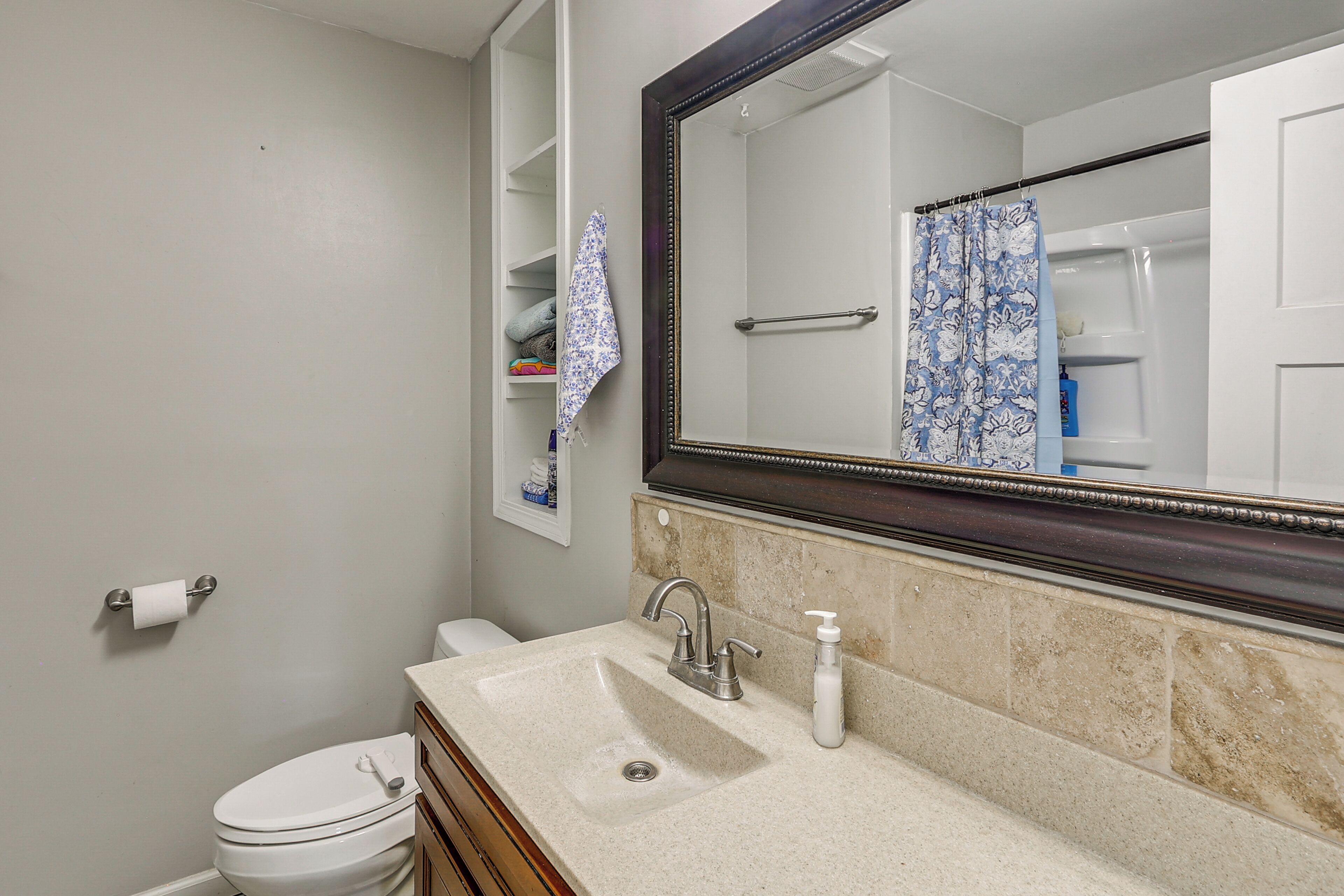 A bathroom with a toilet, sink, mirror, and towel rack.