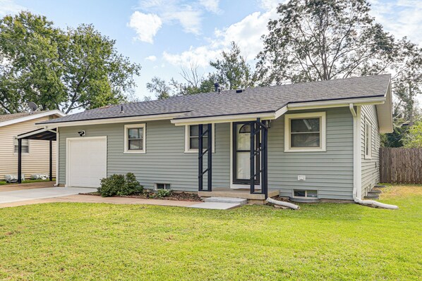 A single-story house with a garage, a front door, and a small front yard.