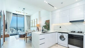 Een moderne keuken met een ingebouwde wasmachine en oven, een eetgedeelte met uitzicht en een groot raam.
