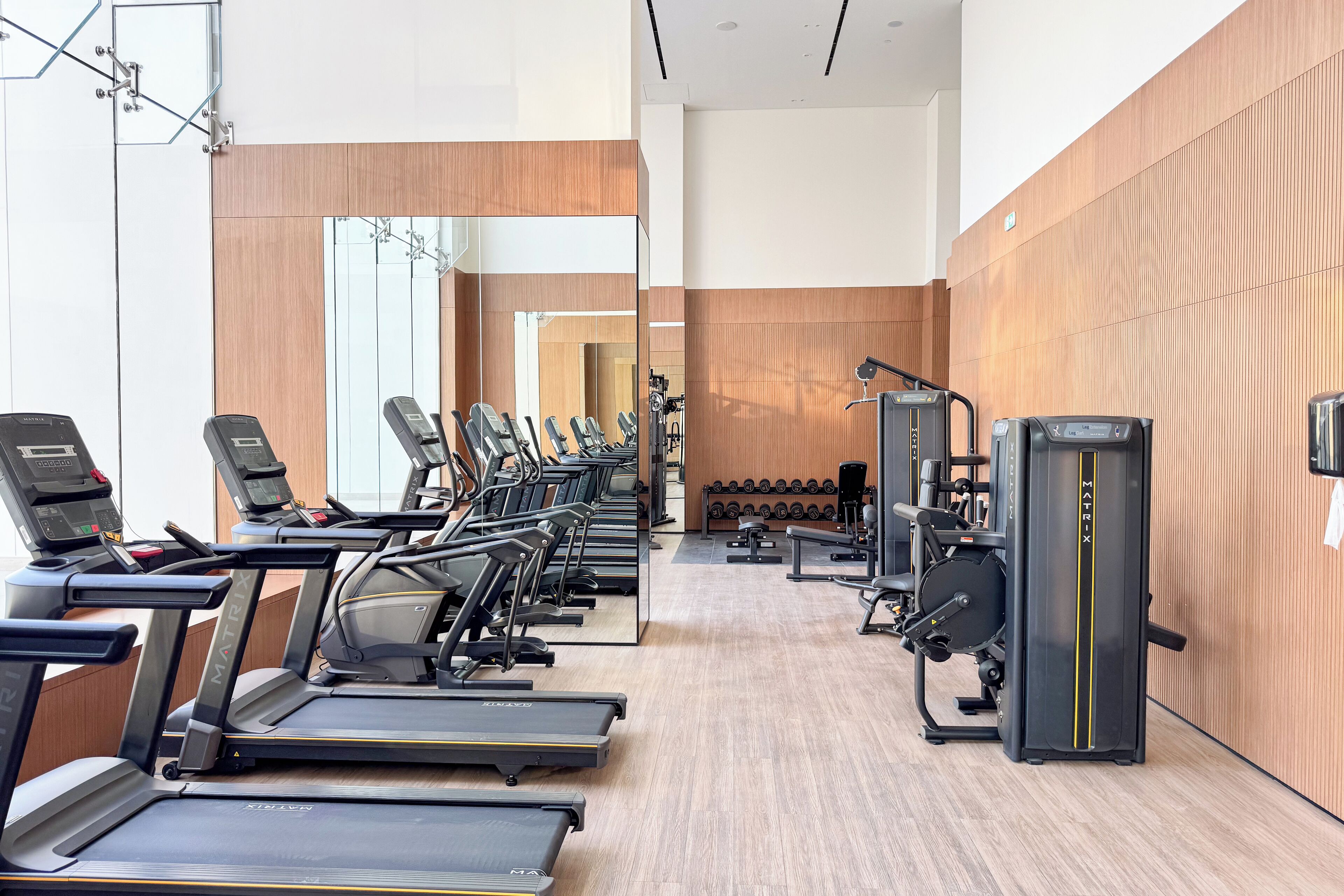 Une salle de sport équipée de tapis de course, d’appareils de musculation et d’haltères.