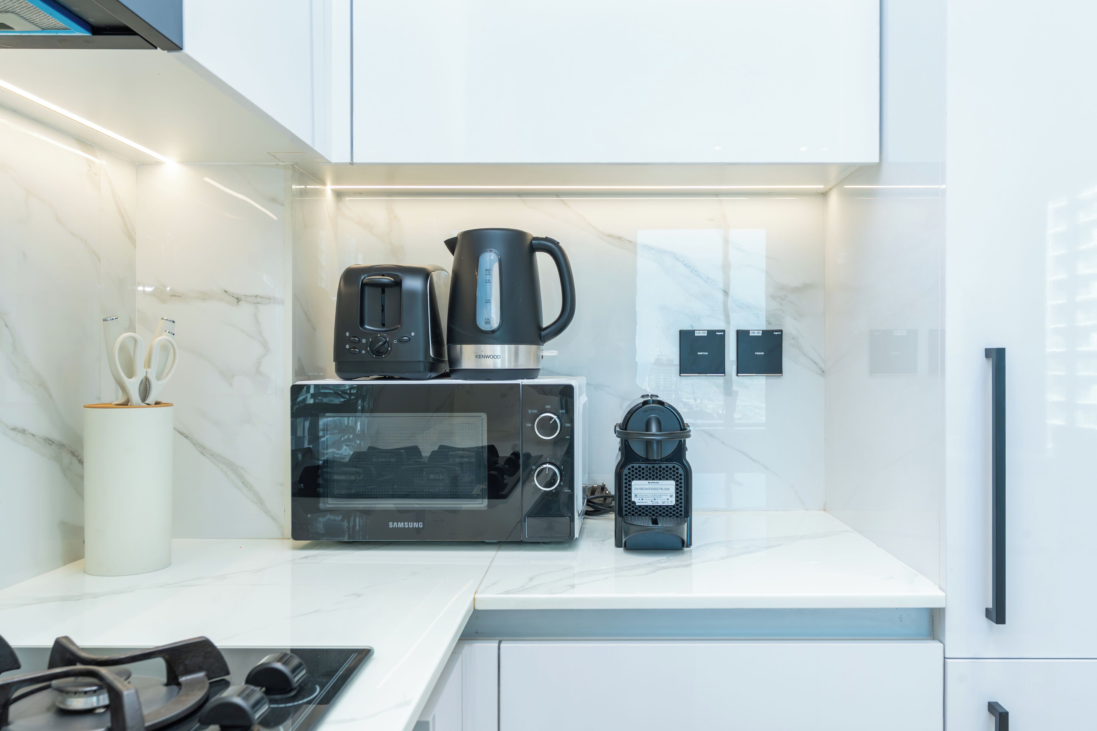 Et moderne køkken med mikrobølgeovn, brødrister og kaffemaskine på bordet.