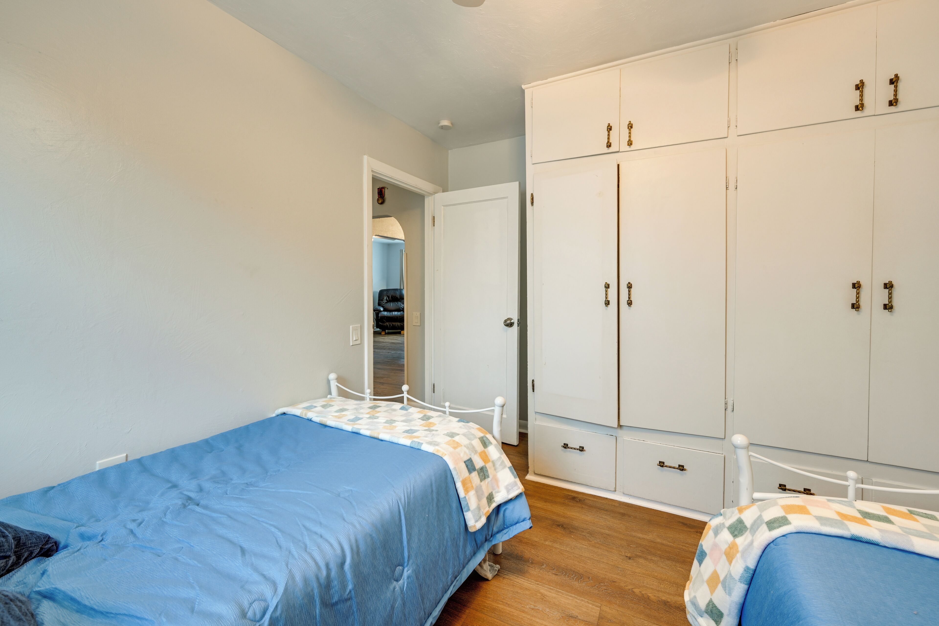 A bedroom with two single beds, a wardrobe, and a door leading to another room.