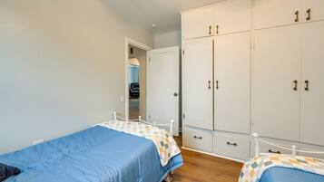 Un dormitorio con dos camas individuales, un armario y una puerta que da a otra habitación.