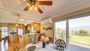 A spacious kitchen with wooden cabinets, a central island, and a dining area with a table set for four. - Hot Tub, Views & Private Dock: Polson Haven! (Polson)