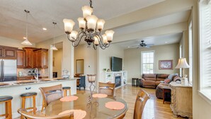 A spacious living area with a dining table, chairs, a chandelier, and a kitchen in the background. - Explore Historic Dtwn! Walkable Loft in Murphy (Murphy)