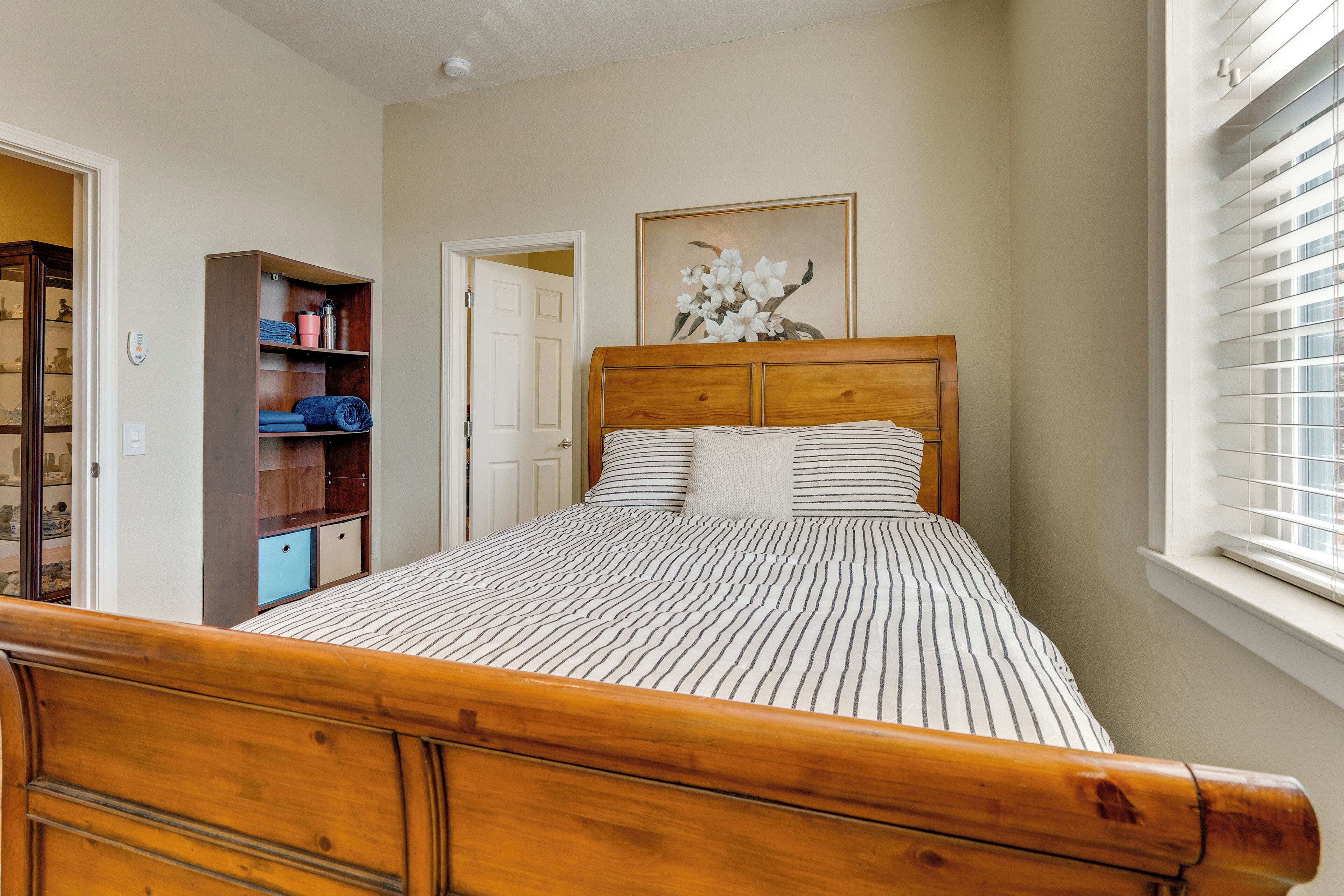 A bedroom with a wooden bed, a wardrobe, and a door leading to another room.