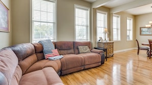 A living room with a large brown sectional sofa, a wooden dining table, and a chandelier. - Explore Historic Dtwn! Walkable Loft in Murphy (Murphy)