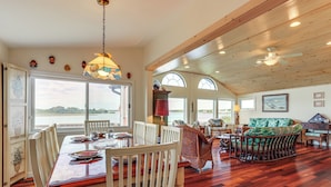 A spacious dining area with a wooden table and chairs, a large window with a view of the water, and a ceiling fan. - Dock + Water Access: Charlestown Beach Escape! (Charlestown)