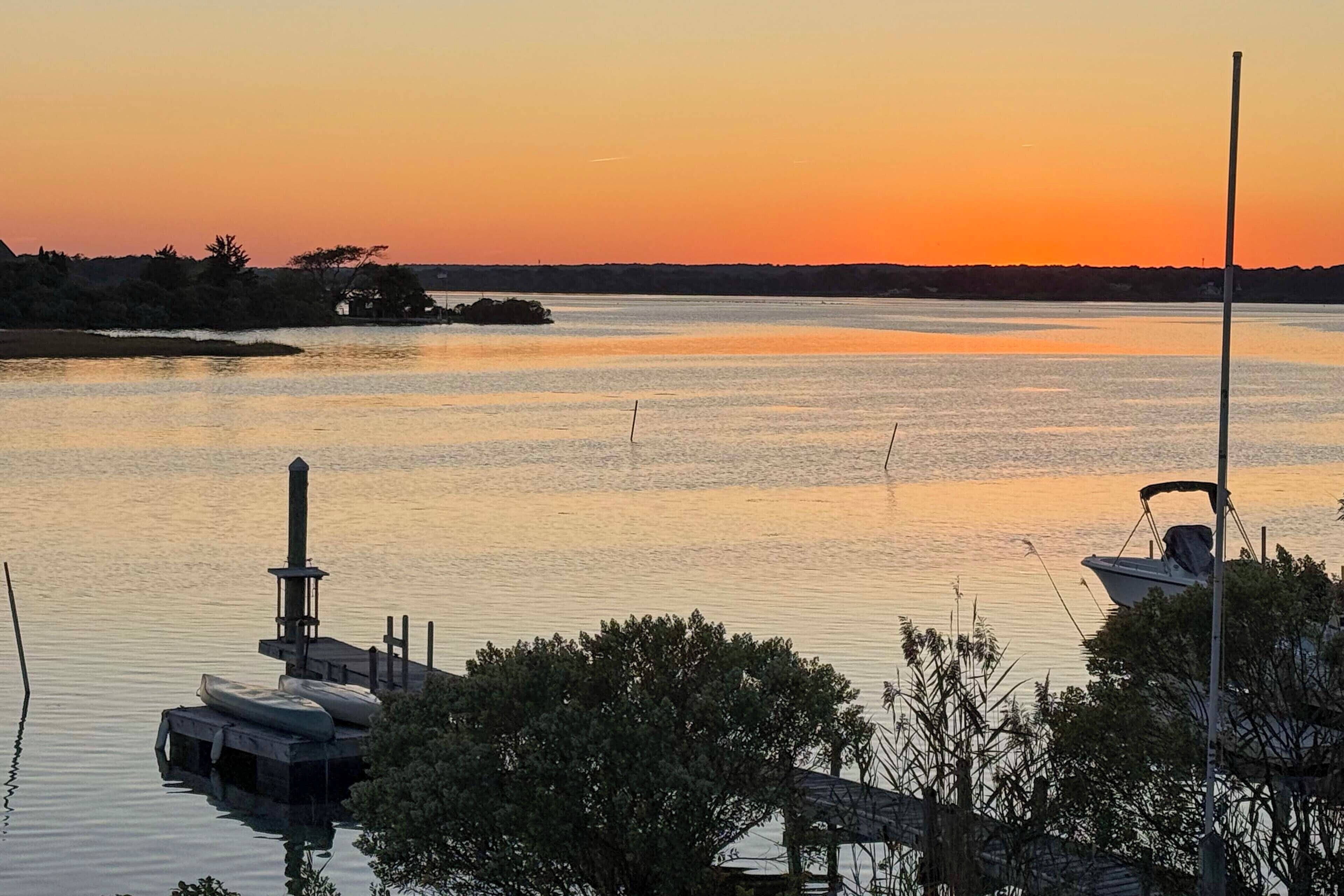 Un lac paisible au coucher du soleil, avec un quai et un bateau.
