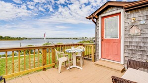 A wooden deck with a table and chairs, a red door, and a view of a lake. - Dock + Water Access: Charlestown Beach Escape! (Charlestown)