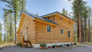 A log cabin with a sloped roof, wooden exterior, and a gravel driveway. - Secluded Mtn-view Cabin 16 Mi to Swan Lake! (Bigfork)