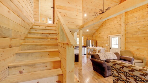 A wooden interior with a staircase, a sofa, and a dining area. - Secluded Mtn-view Cabin 16 Mi to Swan Lake! (Bigfork)