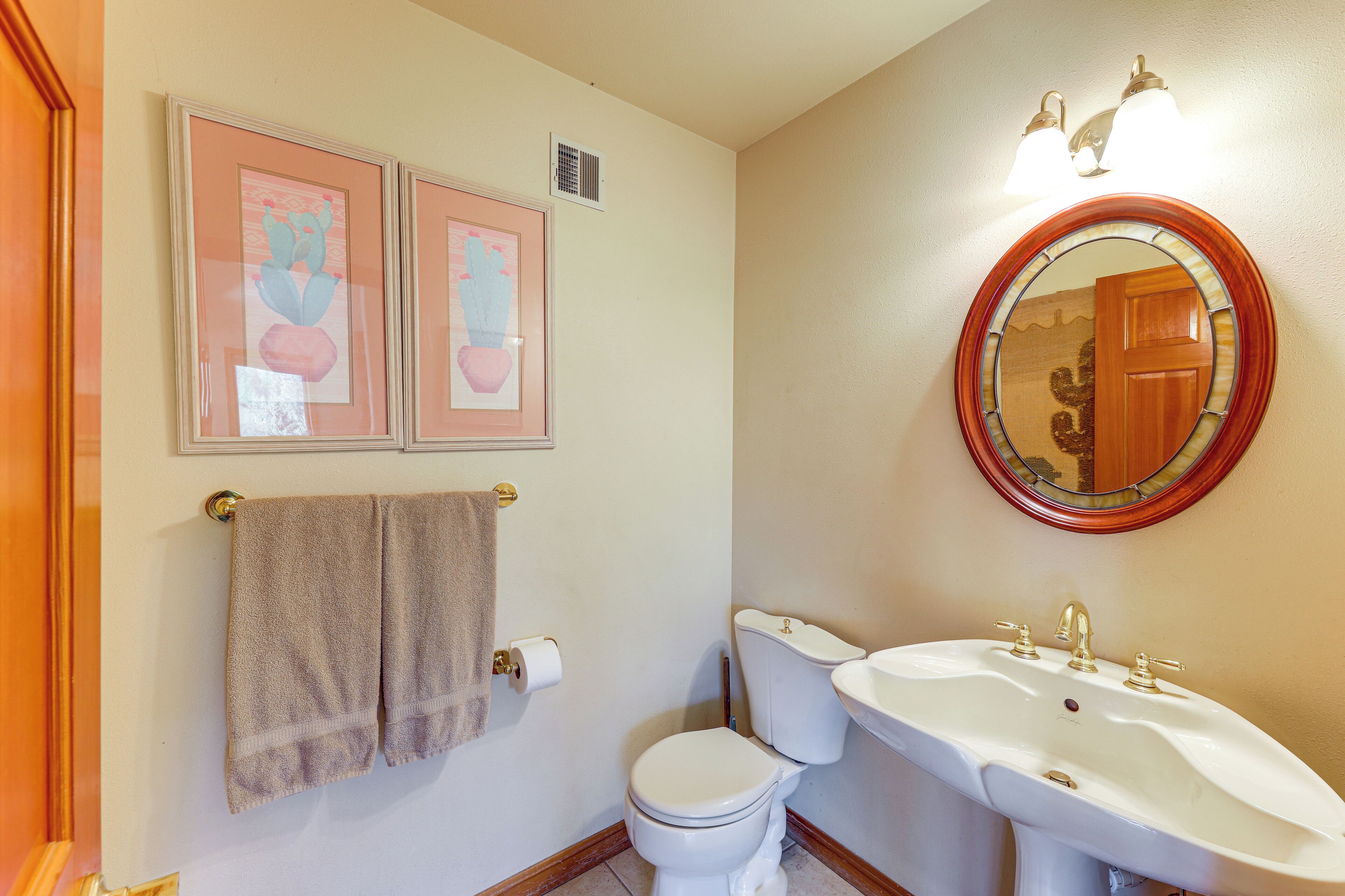 Une salle de bain avec des toilettes, un lavabo et des tableaux encadrés accrochés au mur.