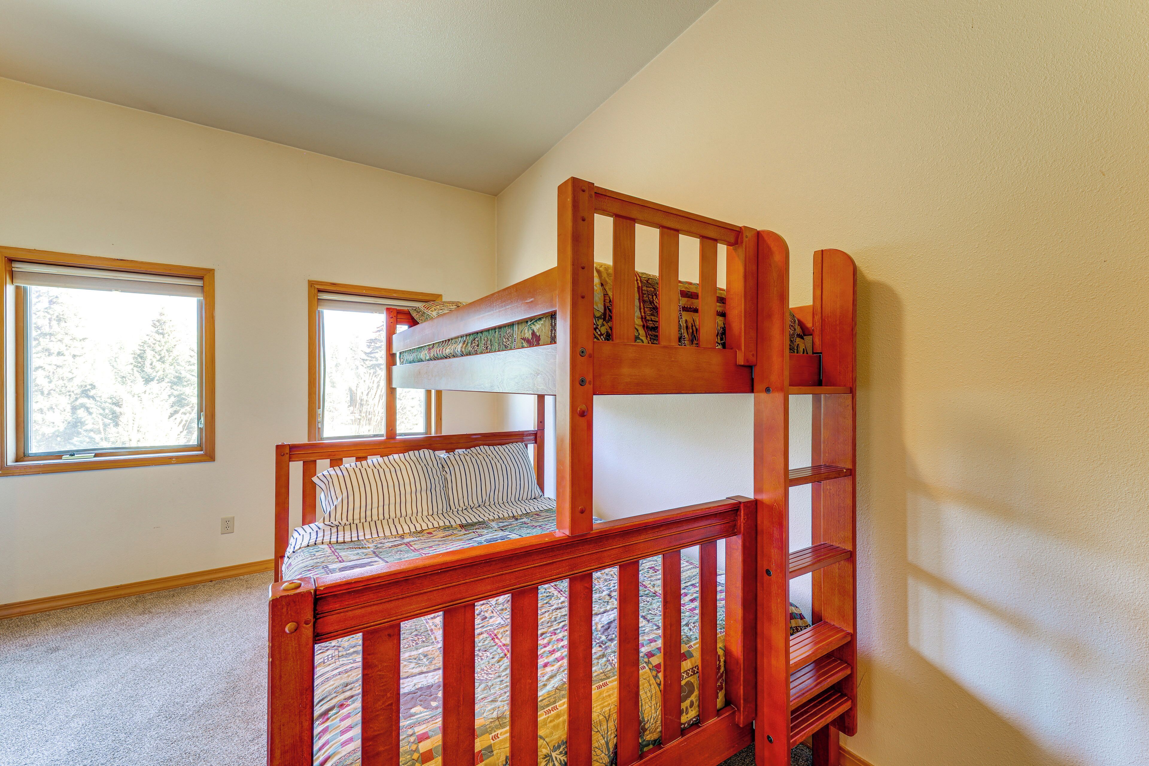 A bunk bed with a wooden frame and a lower bunk with a striped pillow.